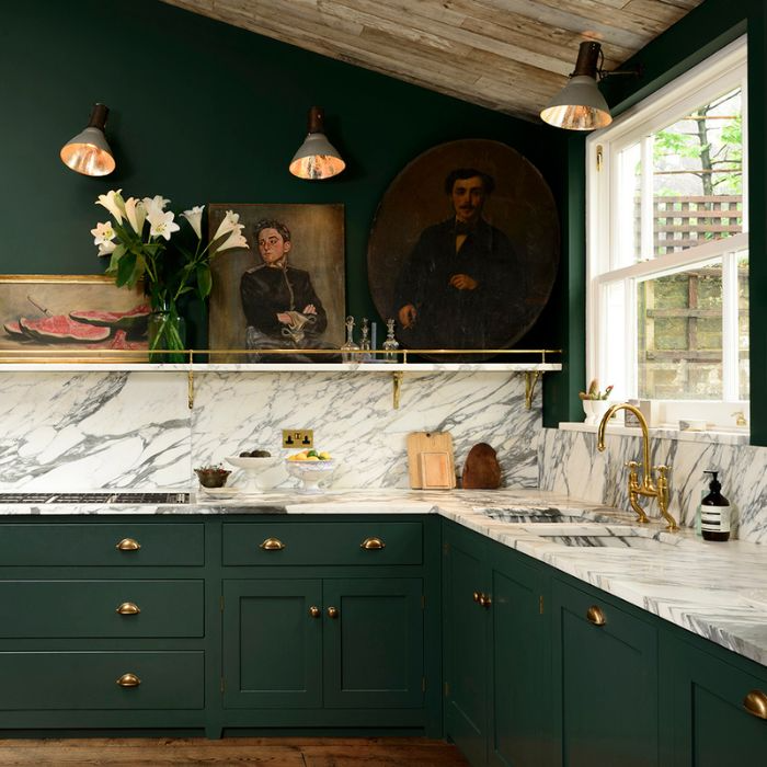 A sophisticated kitchen with vibrant green cabinets and smooth marble countertops