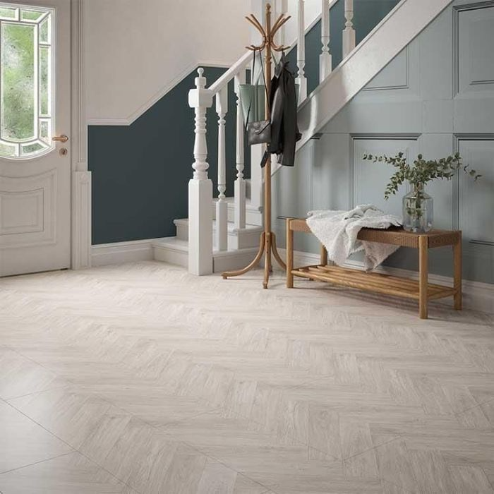 Elegant hallway with white herringbone tile flooring and a wooden staircase