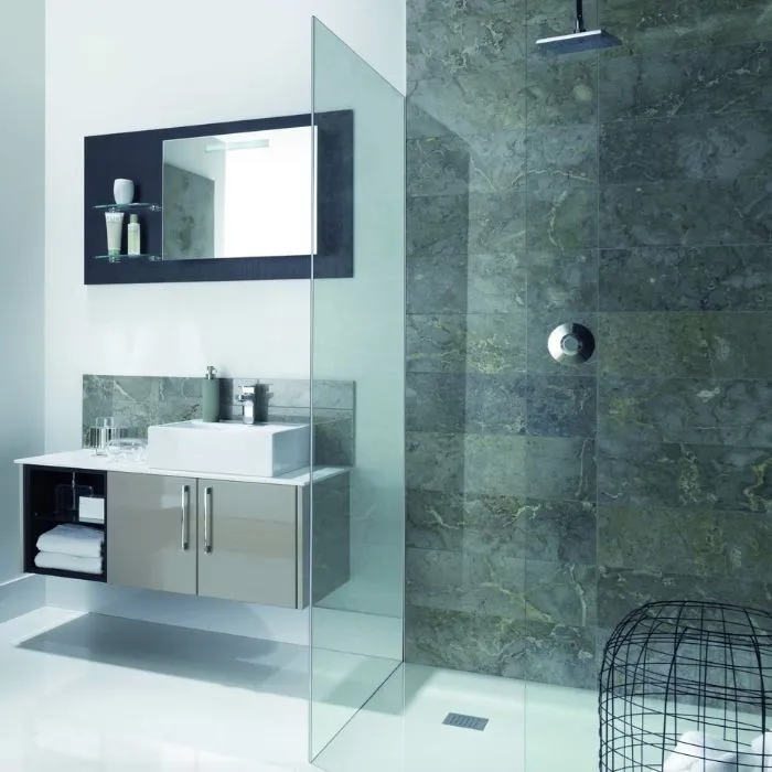 A sleek glass shower stall in a modern bathroom with grey tiled walls and flooring