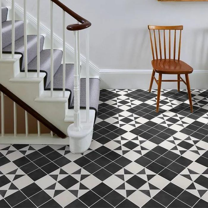 An inviting corridor with a distinctive black and white tiled floor and a graceful staircase