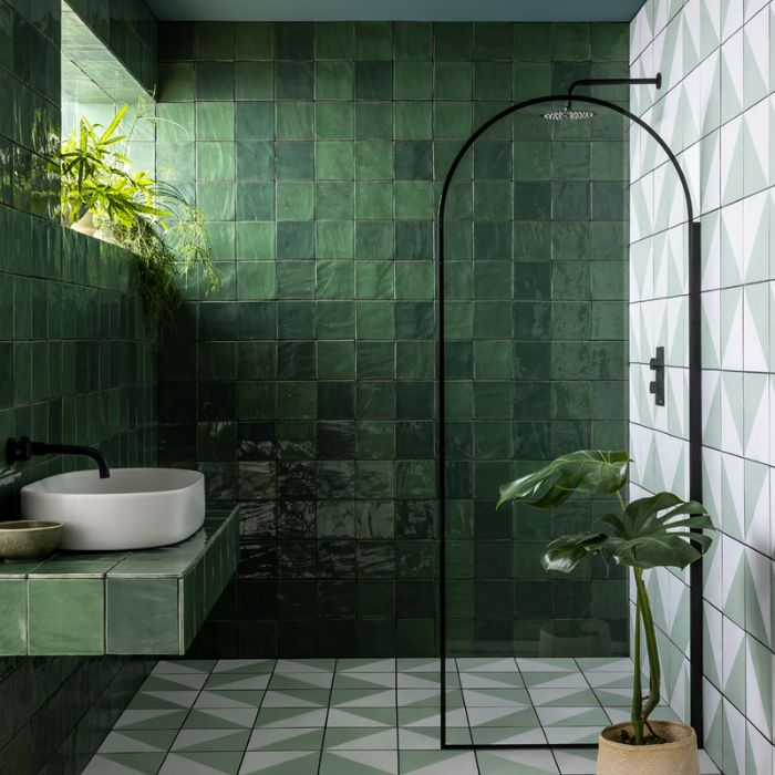 Green-tiled bathroom interior with a refreshing plant