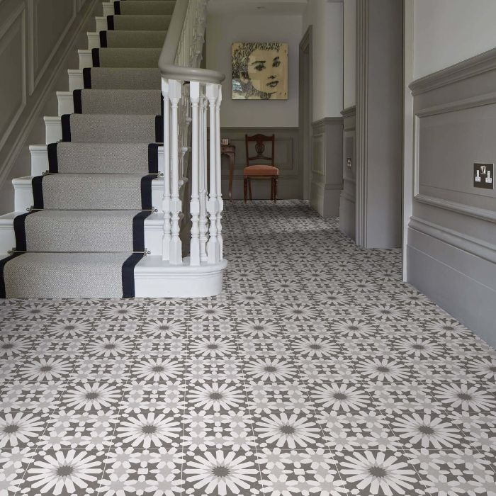 A well-lit hallway featuring a classic staircase and decorative tiled floor patterns