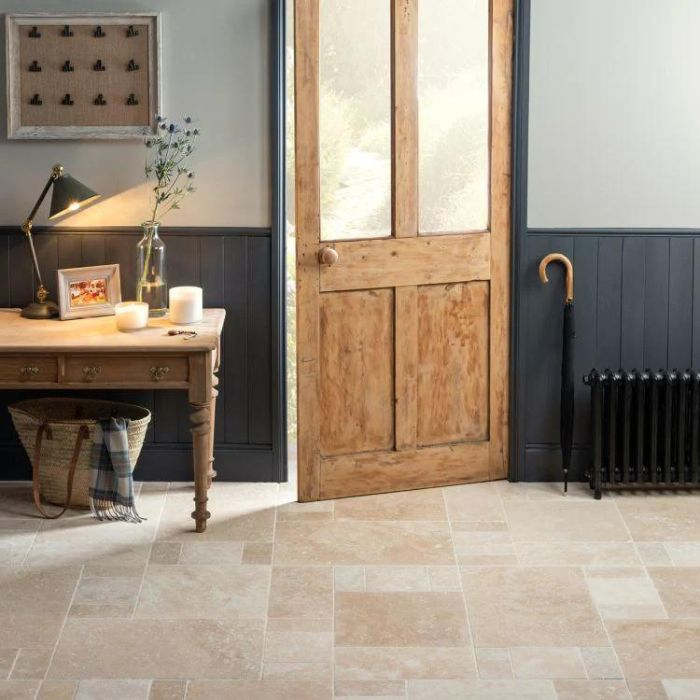 A hallway with stone-effect tiles leading to a wooden door