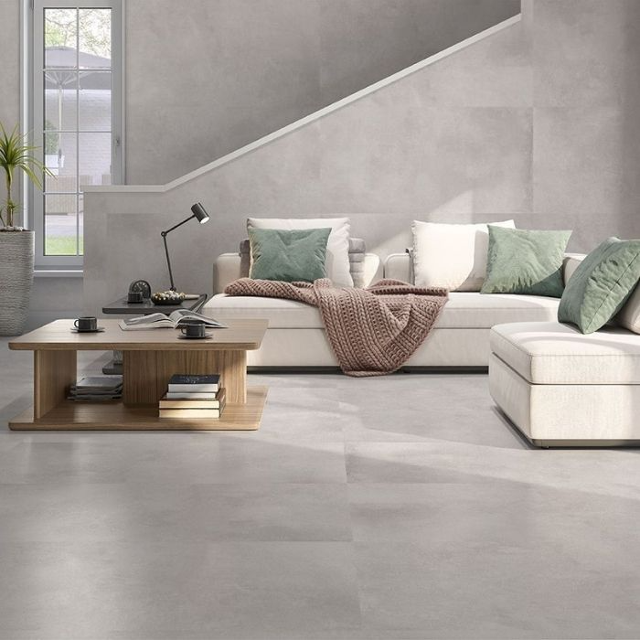 Tastefully designed living room, characterised by a grey palette and white furniture, with concrete floor tiles