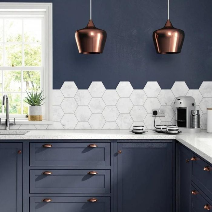 Kitchen with blue cabinets, copper pendant lights, and white hexagon wall tiles