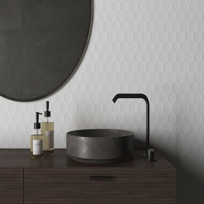 A bright bathroom featuring a white sink and mirror surrounded by pristine white patterned tiles