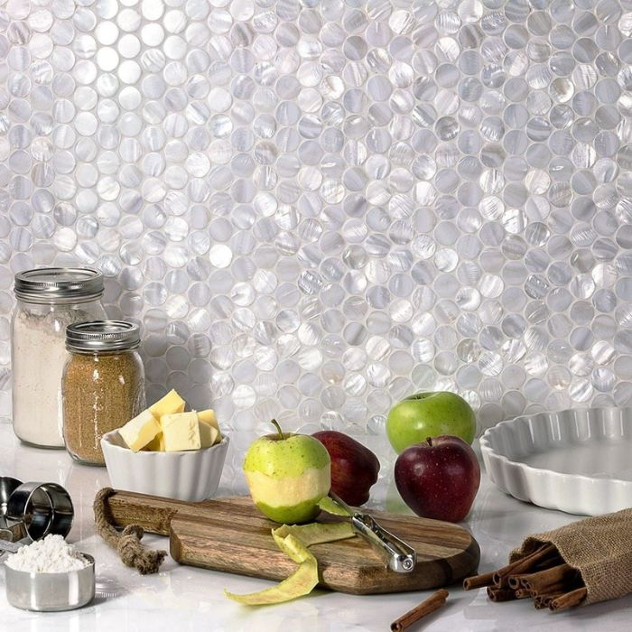 An apple resting on a cutting board with a knife, showcasing the artistic mosaic wall tiles in a bright kitchen setting