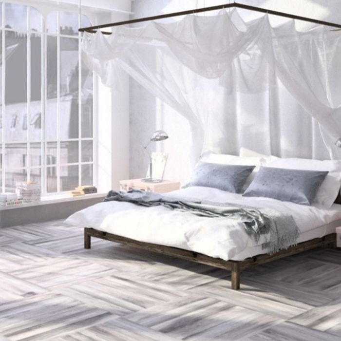 A serene white bedroom featuring a canopy bed and elegant white walls, complemented by sophisticated flooring tiles 