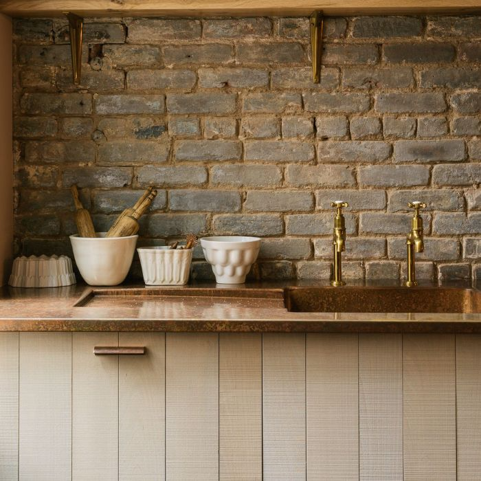 Sink area in a charming kitchen with a brick wall splashback