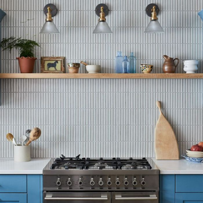 Blue cabinets and wooden shelves in a kitchen with a captivating blue tile splashback