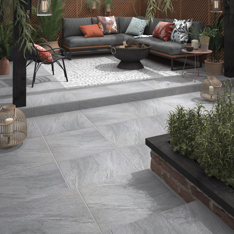 Stylish outdoor seating area on grey tiled patio with lush green plants