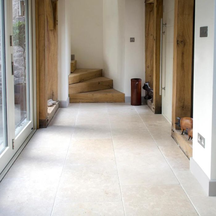 Well-lit hallway with stylish white tiles complementing a warm wooden stairway