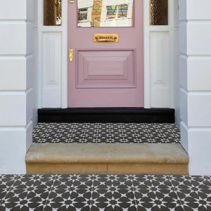 A charming pink door set against a striking black and white tiled floor