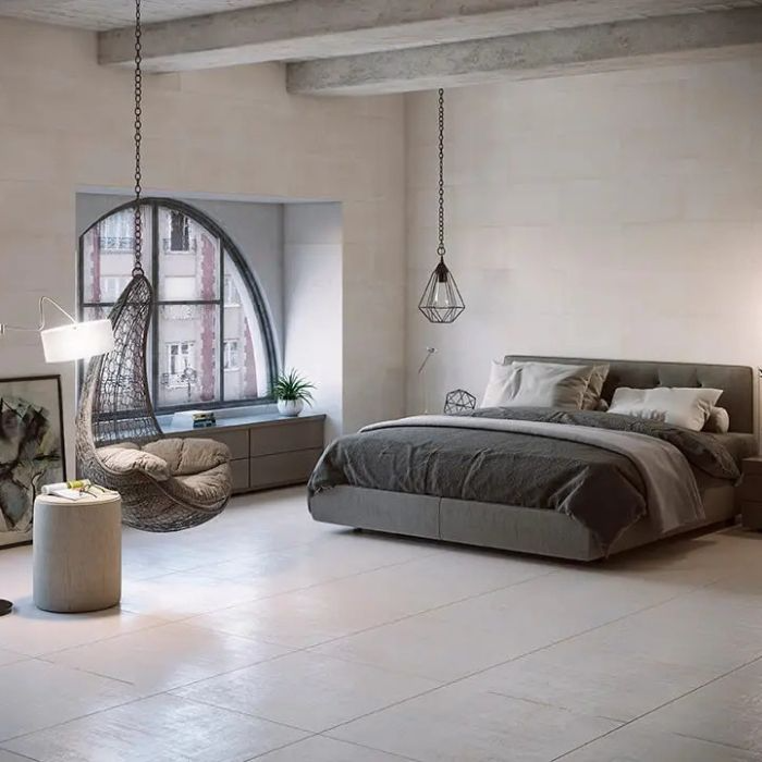 A bedroom featuring a neatly made bed beneath lamps, with elegant tiled flooring