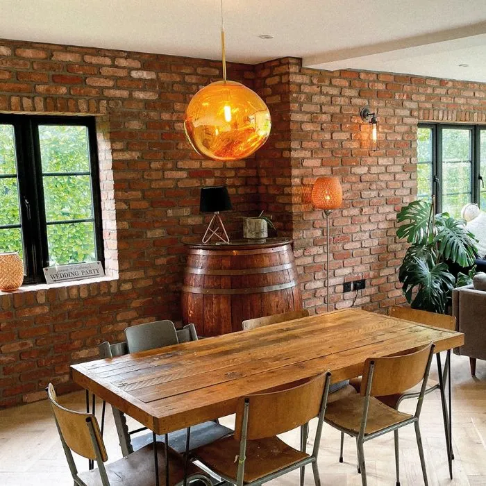 Cosy dining room with a wooden table and chairs against a brick wall