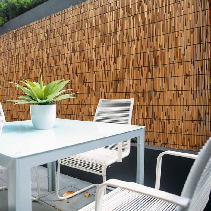 Serene outdoor dining setting with bamboo tile fence backdrop