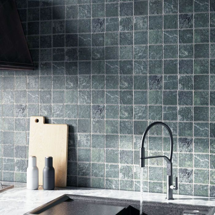 A stylish kitchen with vibrant green mosaic tiles and a sleek black sink