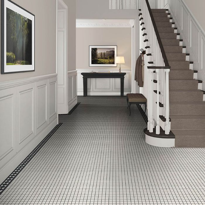 Monochrome tiled hallway featuring classic black and white tiles with a staircase in the background