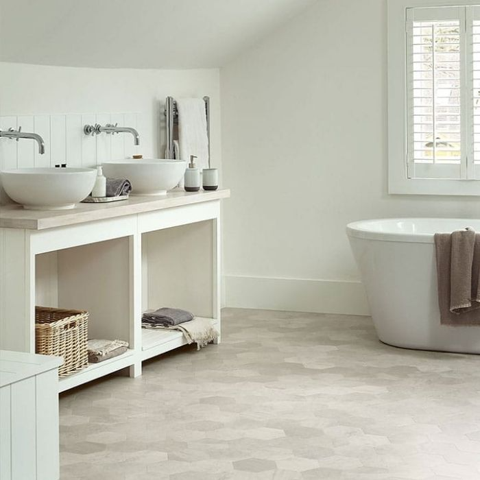 Spotless white bathroom scene including a bathtub and sink set against polished vinyl flooring 