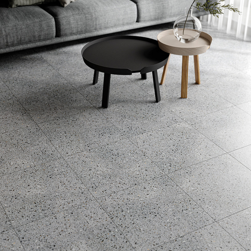 Close-up view of terrazzo floor tiles in a living room with black and white furniture