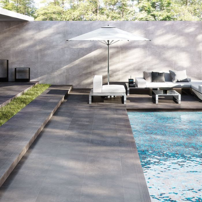 Contemporary poolside retreat with sleek black floor tiles and sun loungers