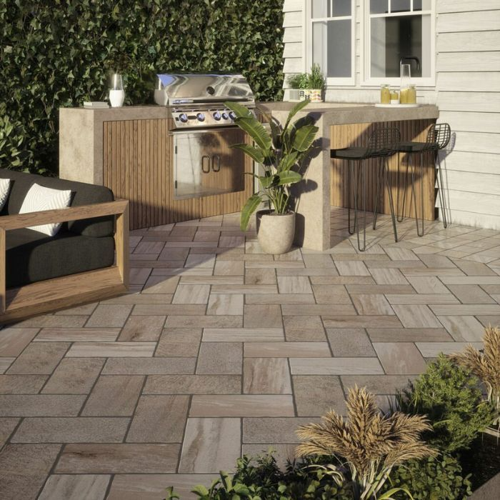 Outdoor furniture and a barbecue grill on a beautifully tiled patio