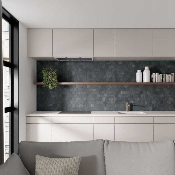 A modern kitchen featuring white cabinets, black countertops, and striking hexagon wall tiles