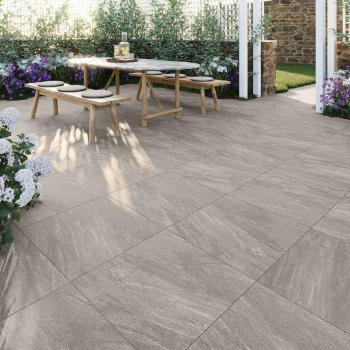 Outdoor dining area on grey tiled patio with wooden table and chairs