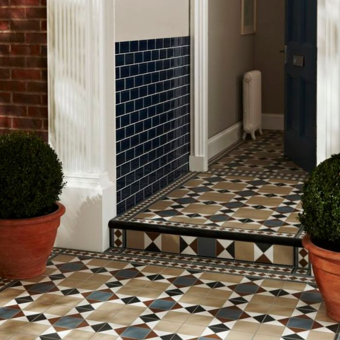 Brightly coloured tiles in an entryway, complemented by thriving potted plants and a stylish door