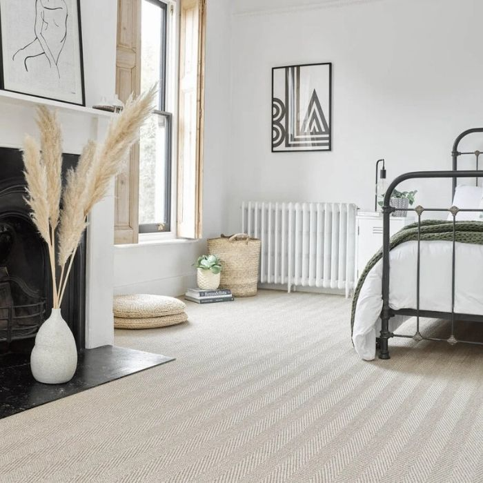 A plush bed and a fireplace set on elegant white and beige tile flooring 