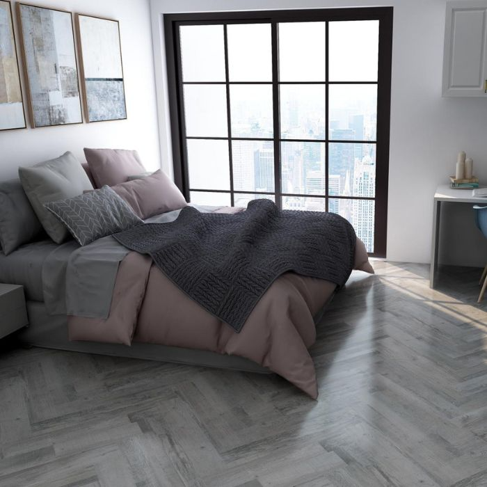 Contemporary bedroom with a grey bed, white dresser, and grey herringbone floor tiles