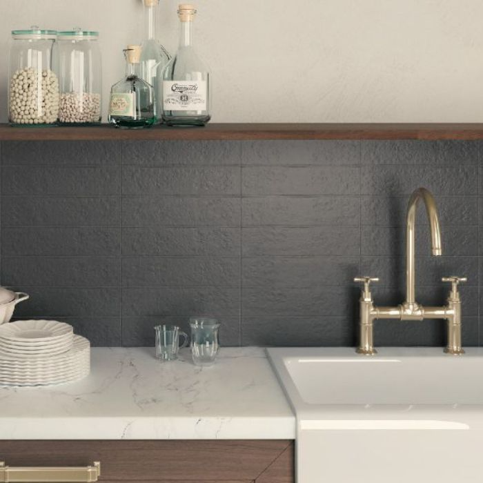 Kitchen sink and wooden countertops in front of textured wall tiles