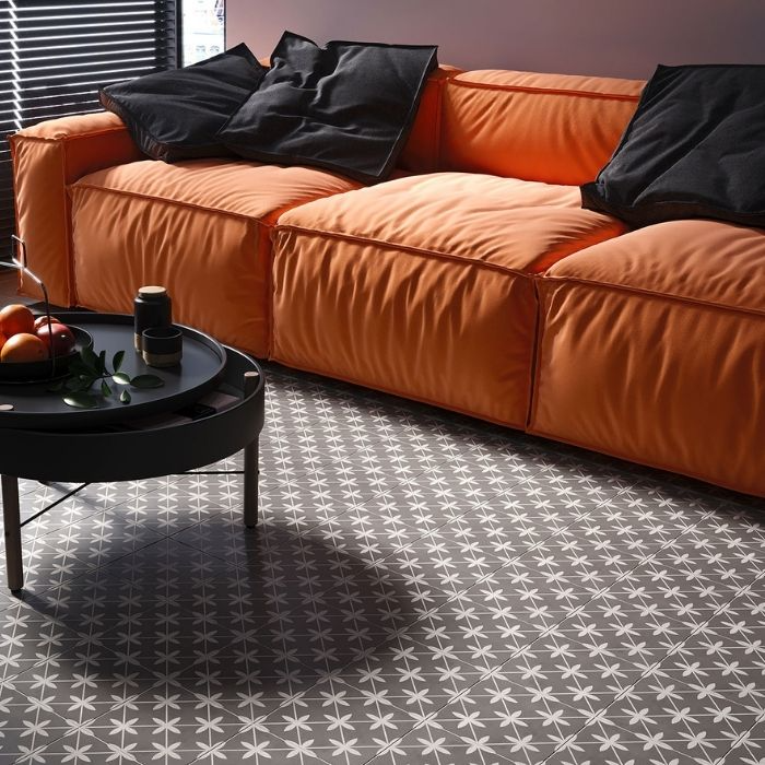 Living room with orange sofa and dark patterned floor tiles