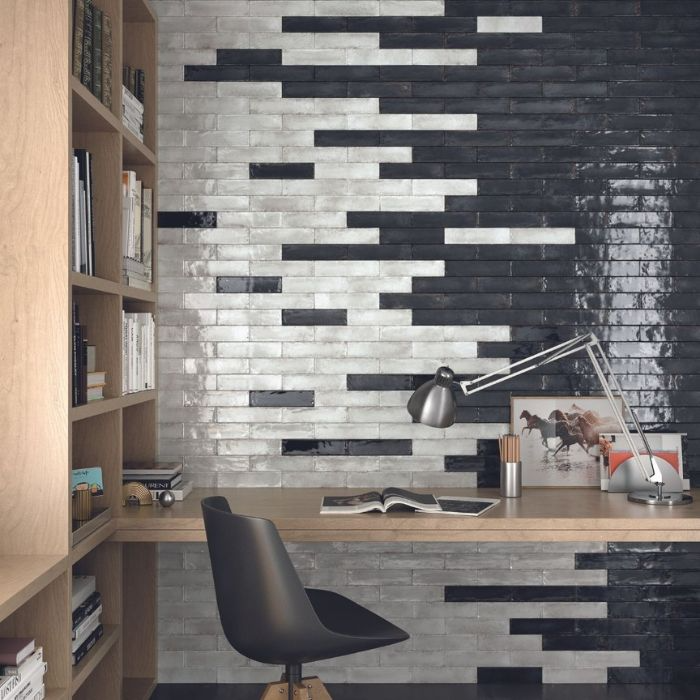 A black and white office featuring a desk and a bookshelf against a brick-effect wall