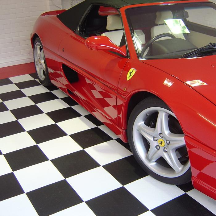 Sleek red sports car elegantly parked on a contrasting checkered floor in a modern garage