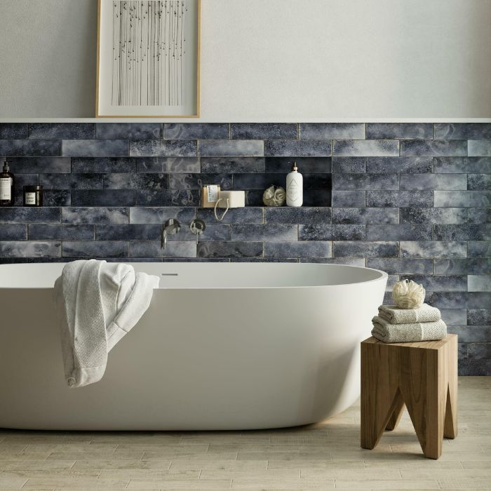 A contemporary bathroom featuring a pristine white bathtub against blue brick-effect wall tiles