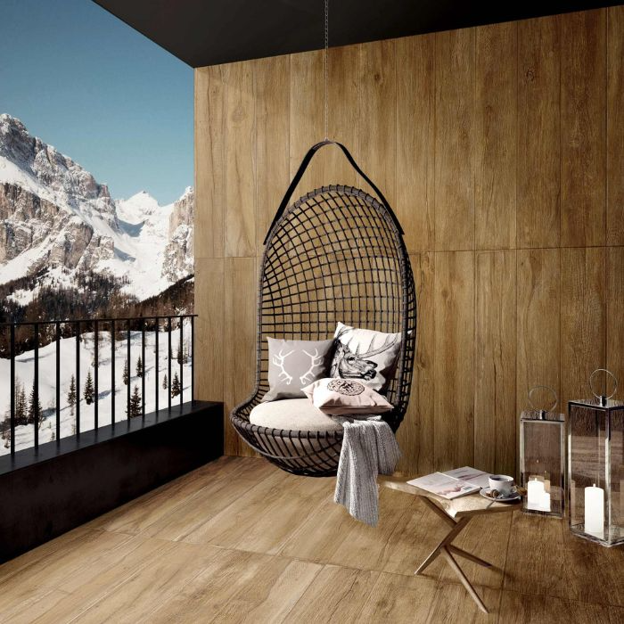 Cosy wood tile balcony with a hanging chair, framed by majestic snow-capped peaks