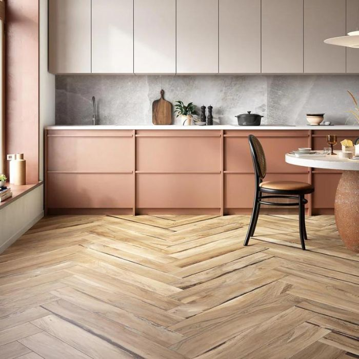 Pink kitchen cabinets contrast with warm wooden floor in bright kitchen space