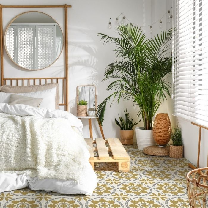 Bright white and yellow bedroom featuring a neatly made bed and an elegant mirror, with stylish floor tiles enhancing the decor 