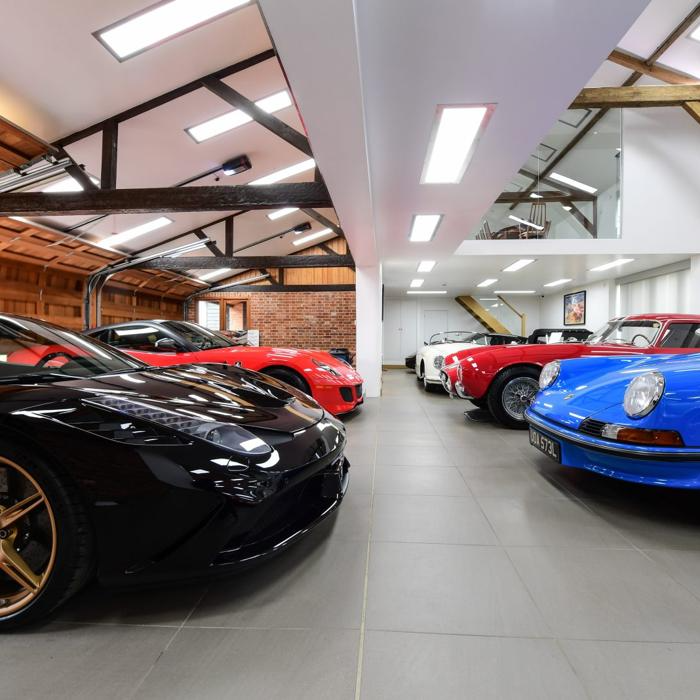 Sports cars gleam under garage lights, their shiny paint reflecting on the polished floor