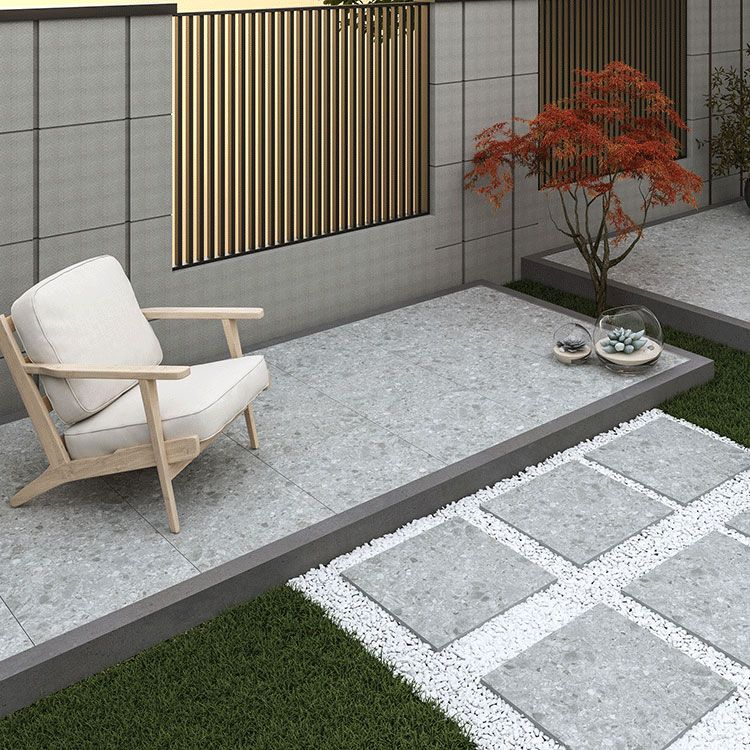 A peaceful patio setting with a chair and a table on grey terrazzo-effect garden tiles