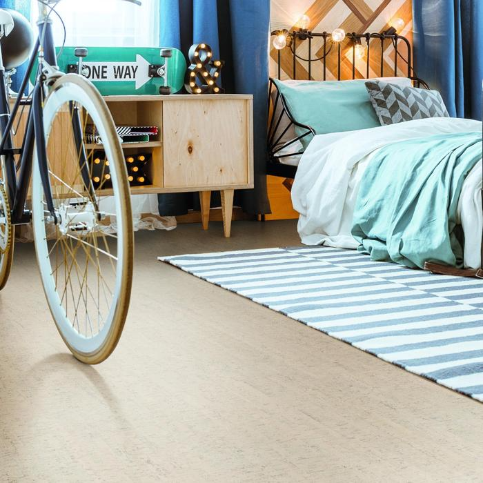 A cosy bedroom featuring cork flooring with a bicycle parked beside the bed