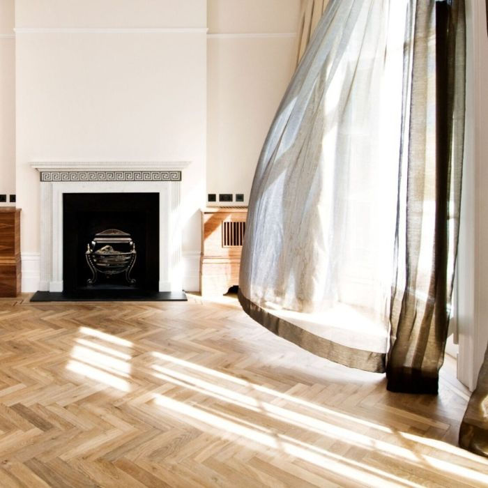 Stylish living room with herringbone wooden floors, adorned with a cosy fireplace