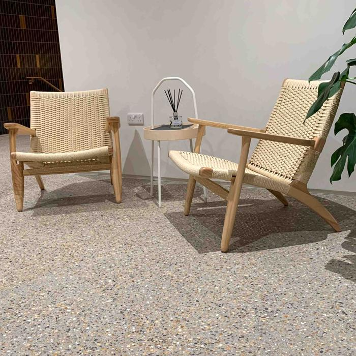 Two wicker chairs on speckled concrete floor