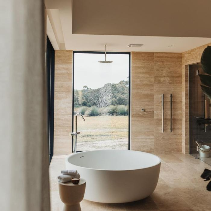 Freestanding tub in travertine-tiled bathroom