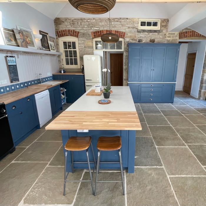 Blue cabinets in kitchen with natural limestone tiles underneath