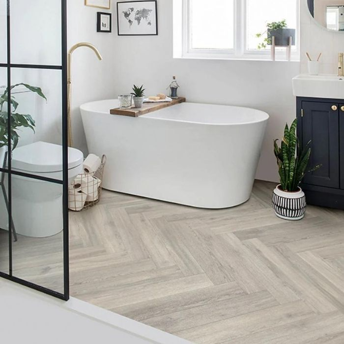 Bathroom with light grey herringbone flooring and freestanding tub