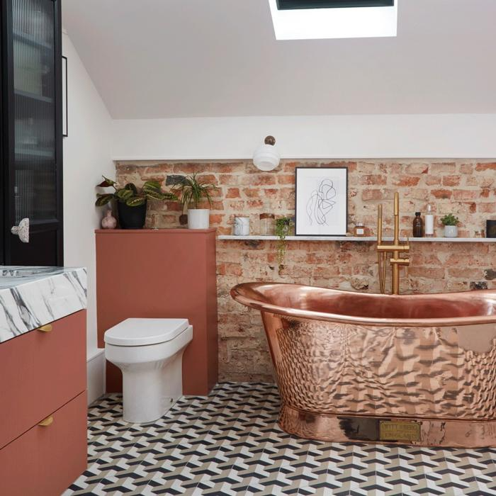 Modern bathroom with copper bathtub, brick wall, and geometric floor tiles