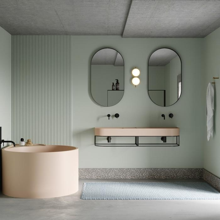 Pastel green walls, peach tub, and dual mirrors in a bathing space