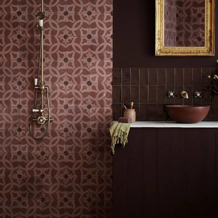 Dark red patterned tiles and brass fixtures in a luxurious bathroom